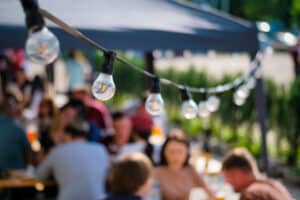hanged lamps outdoor restaurant with multiple visitors background bbq